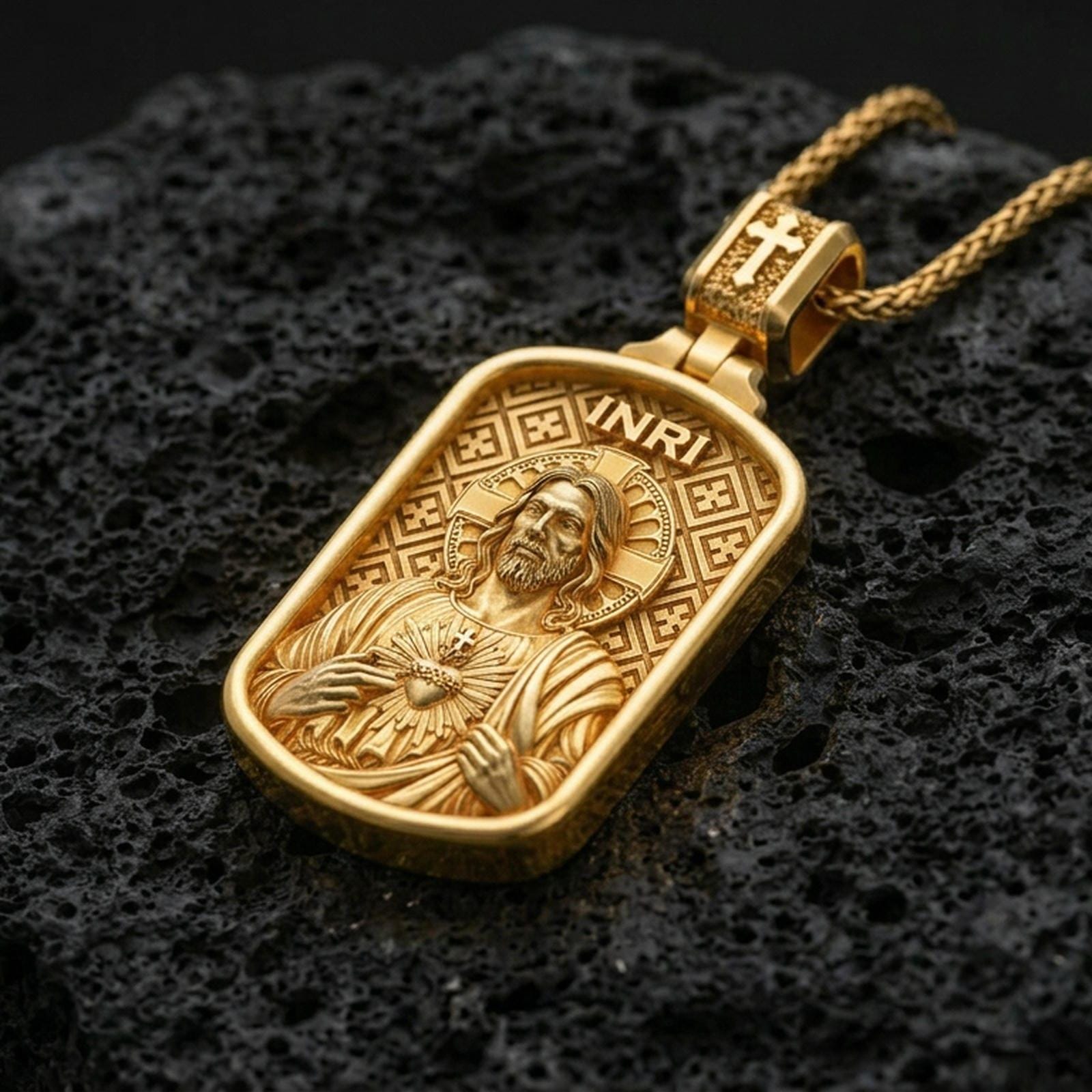 Gold plated Christian pendant with Sacred Heart Jesus design, detailed relief, and INRI lettering showcased on black volcanic rock in a refined macro jewelry image