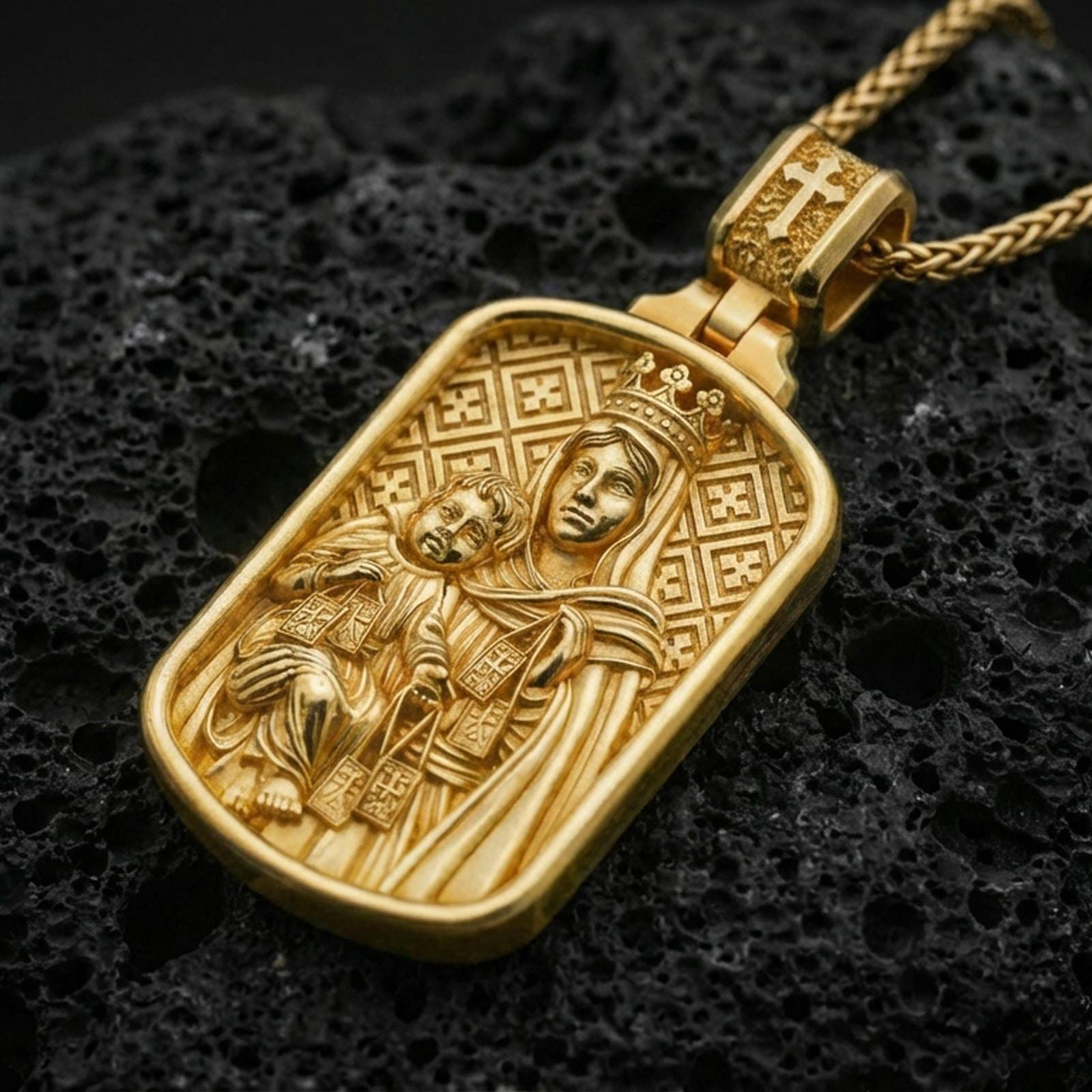 Gold plated Madonna and Child pendant with crowned Mary figure and detailed devotional relief showcased on black volcanic rock in a refined macro jewelry image
