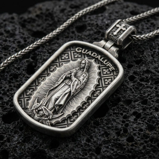 Oxidized Our Lady of Guadalupe pendant with framed devotional figure and Guadalupe inscription displayed on dark volcanic rock in a close-up luxury jewelry composition