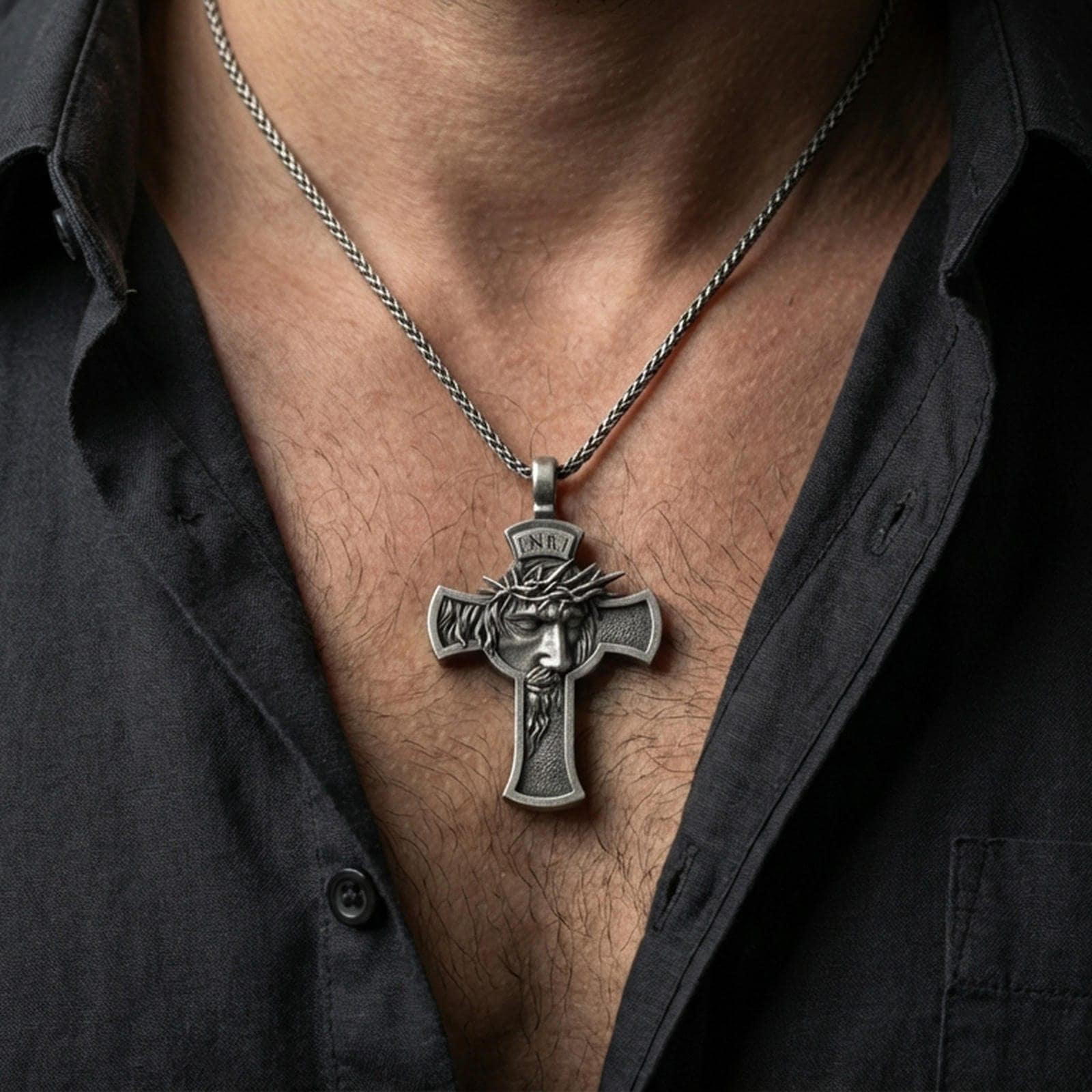Oxidized Jesus crucifix pendant with crown of thorns worn on the neck in a lifestyle jewelry shot, styled against the chest for a bold and devotional look