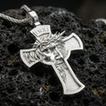 Load image into Gallery viewer, Polished silver Christian cross pendant with detailed Jesus portrait, crown of thorns, and open cross silhouette placed on textured volcanic rock in a premium studio product shot
