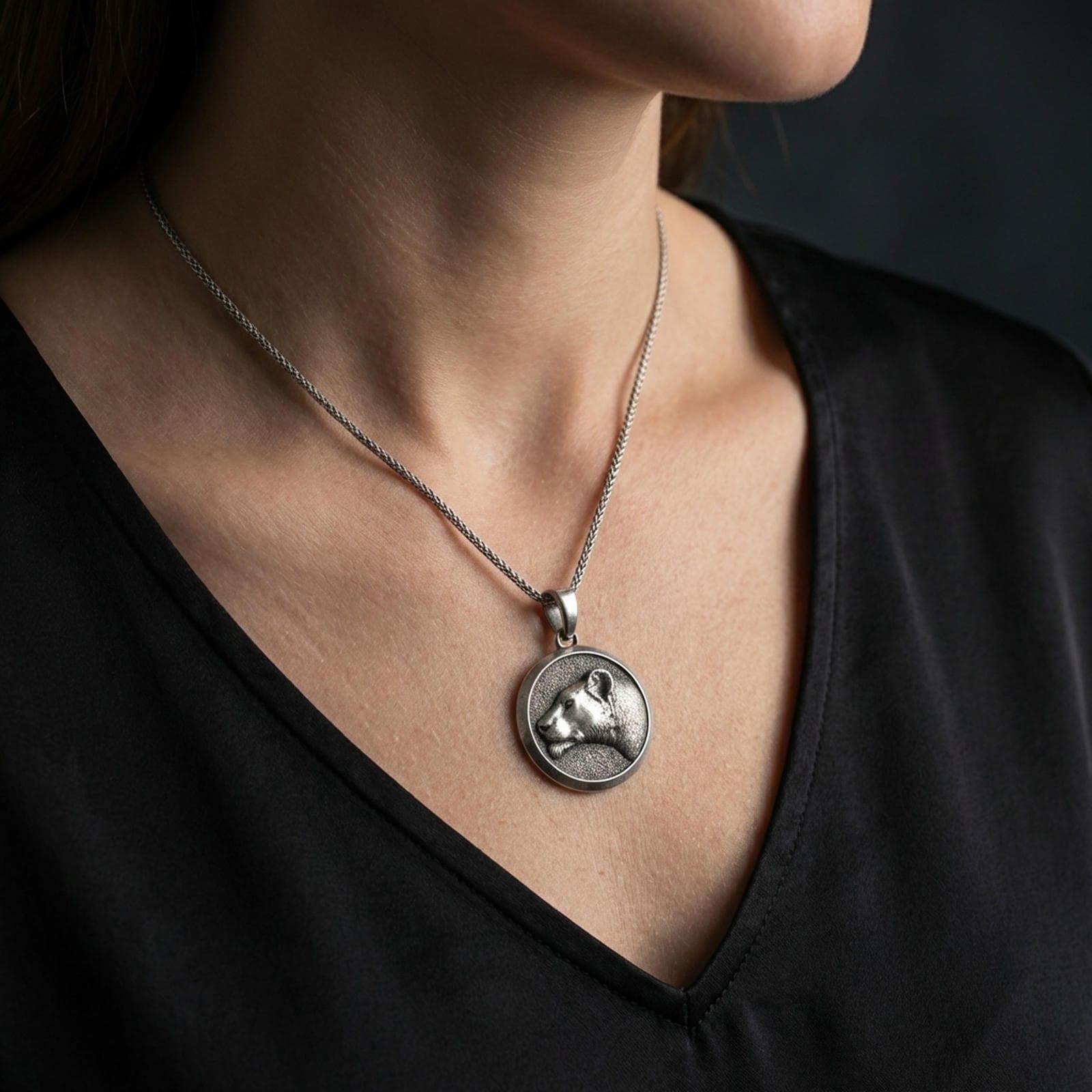 Oxidized lioness pendant with graceful feline profile worn on the neck in a lifestyle jewelry shot, styled against the chest for a bold and symbolic statement look