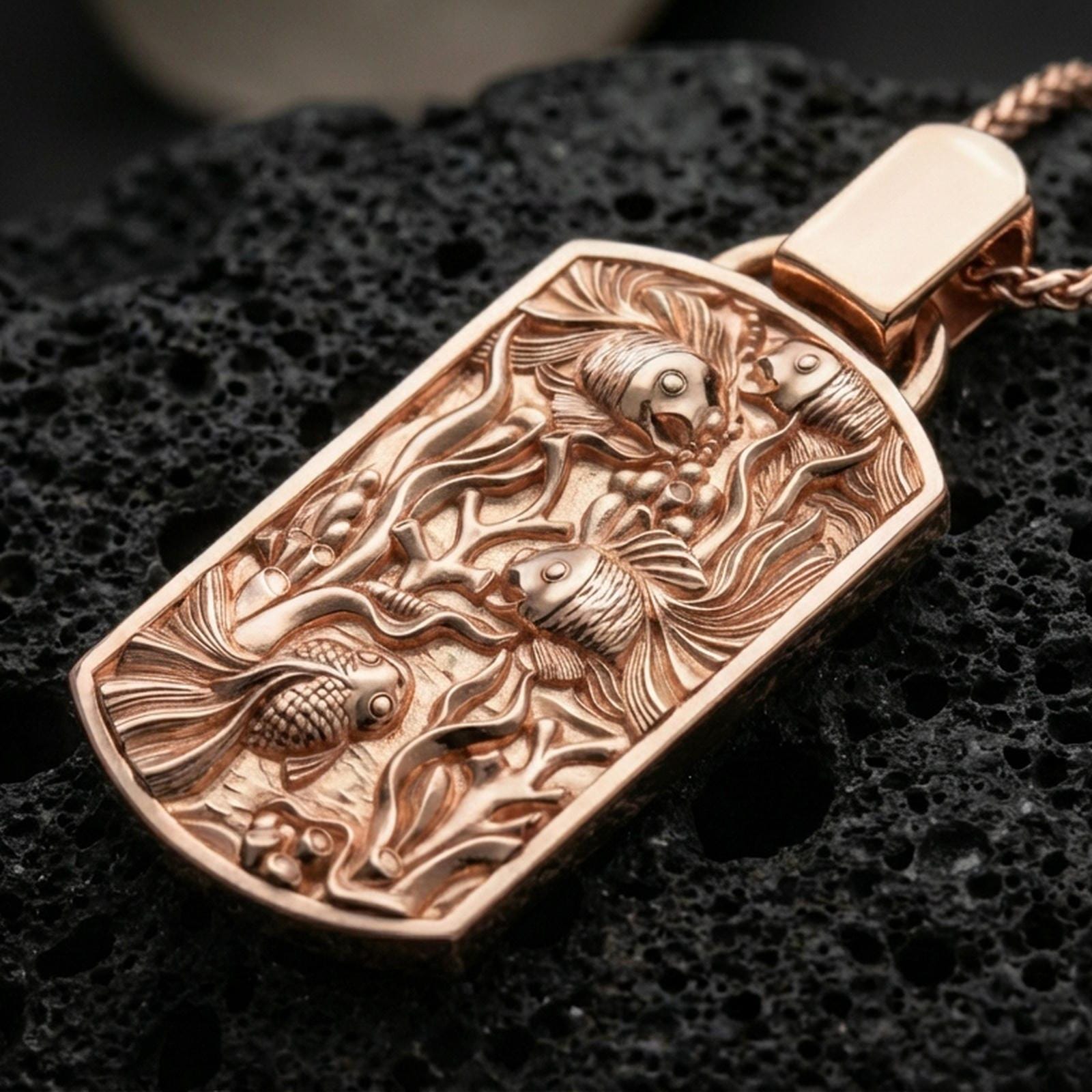 Rose gold plated fish tank necklace with sculpted marine life details, flowing botanical water elements, and elongated rectangular silhouette resting on volcanic rock in an elegant close-up product presentation
