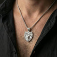 Load image into Gallery viewer, Polished silver stag necklace with Celtic knot relief and antler motif worn on the neck in a close lifestyle frame, highlighting the shield silhouette and refined Norse craftsmanship
