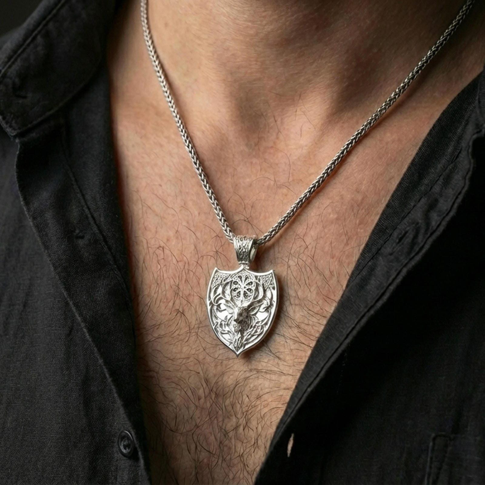 Polished silver stag necklace with Celtic knot relief and antler motif worn on the neck in a close lifestyle frame, highlighting the shield silhouette and refined Norse craftsmanship