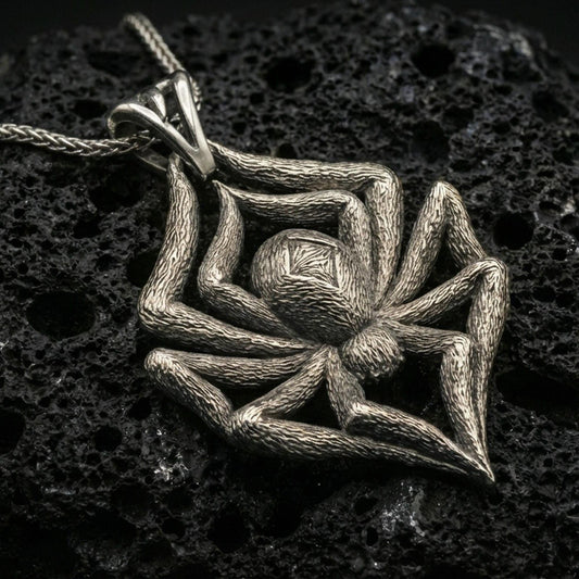 Oxidized spider pendant with textured legs, sculpted body relief, and bold arachnid silhouette displayed on dark volcanic rock in a close-up luxury jewelry composition