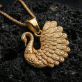 Load image into Gallery viewer, Gold plated swan pendant with ornate feather pattern, graceful neck curve, and elegant nature-inspired silhouette showcased on black volcanic rock in a refined macro jewelry image
