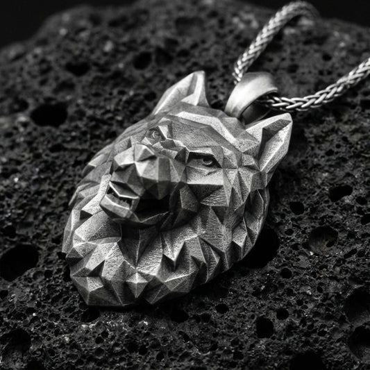 Oxidized polygonal wolf pendant with faceted geometric wolf head, angular sculpted planes, and bold spirit animal silhouette displayed on dark volcanic rock in a close-up luxury jewelry composition