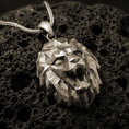 Load image into Gallery viewer, Bronze polygonal lion pendant with faceted geometric lion head, angular sculpted planes, and bold spirit animal silhouette displayed on dark volcanic rock in a close-up luxury jewelry composition
