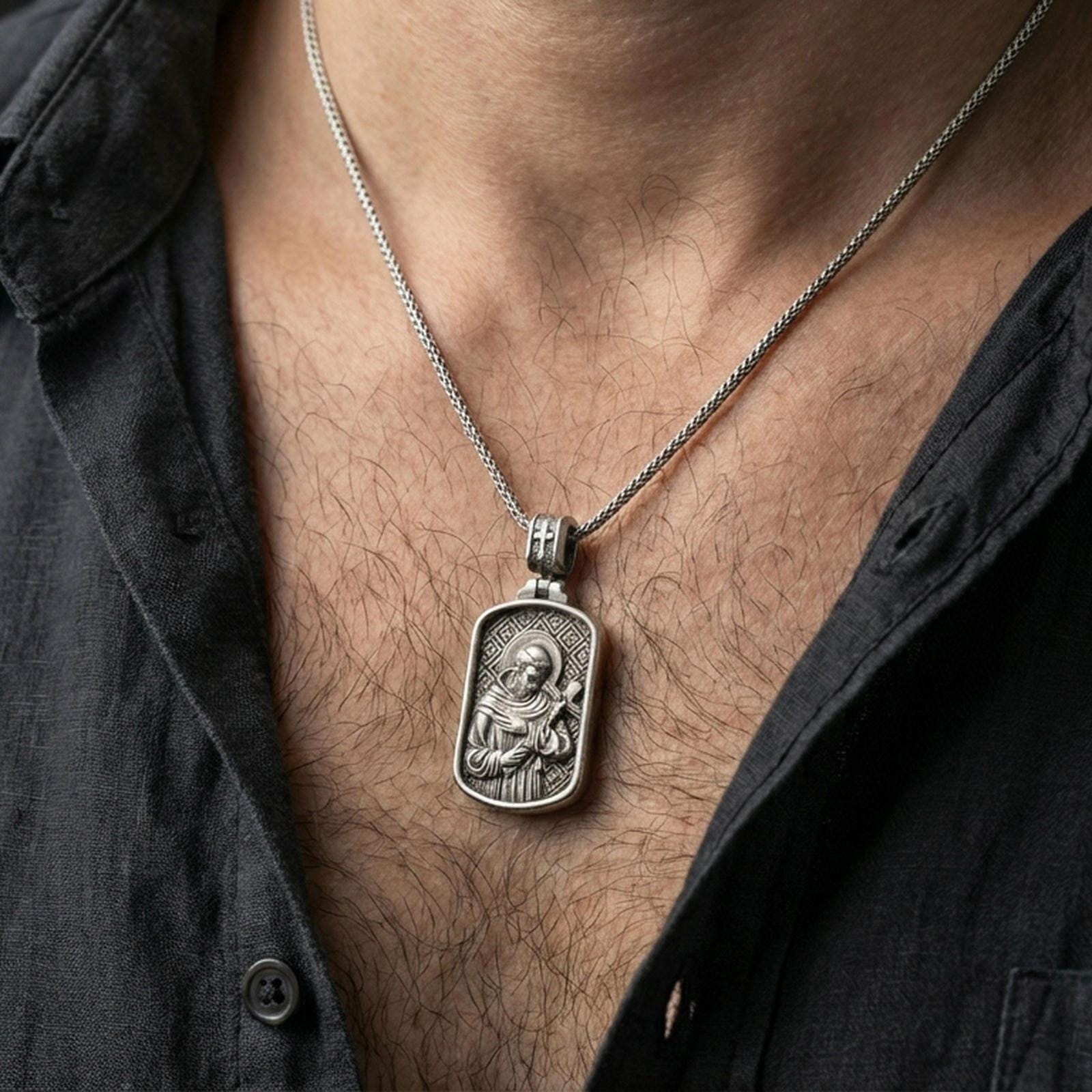 Oxidized Saint Francis pendant worn on the neck in a lifestyle jewelry shot, styled against the chest for a devotional and timeless look