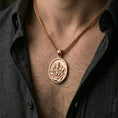 Load image into Gallery viewer, Rose gold plated saint medal pendant with robed figure, lion motif, and engraved book worn on the neck in a refined lifestyle shot with a warm and elegant presentation
