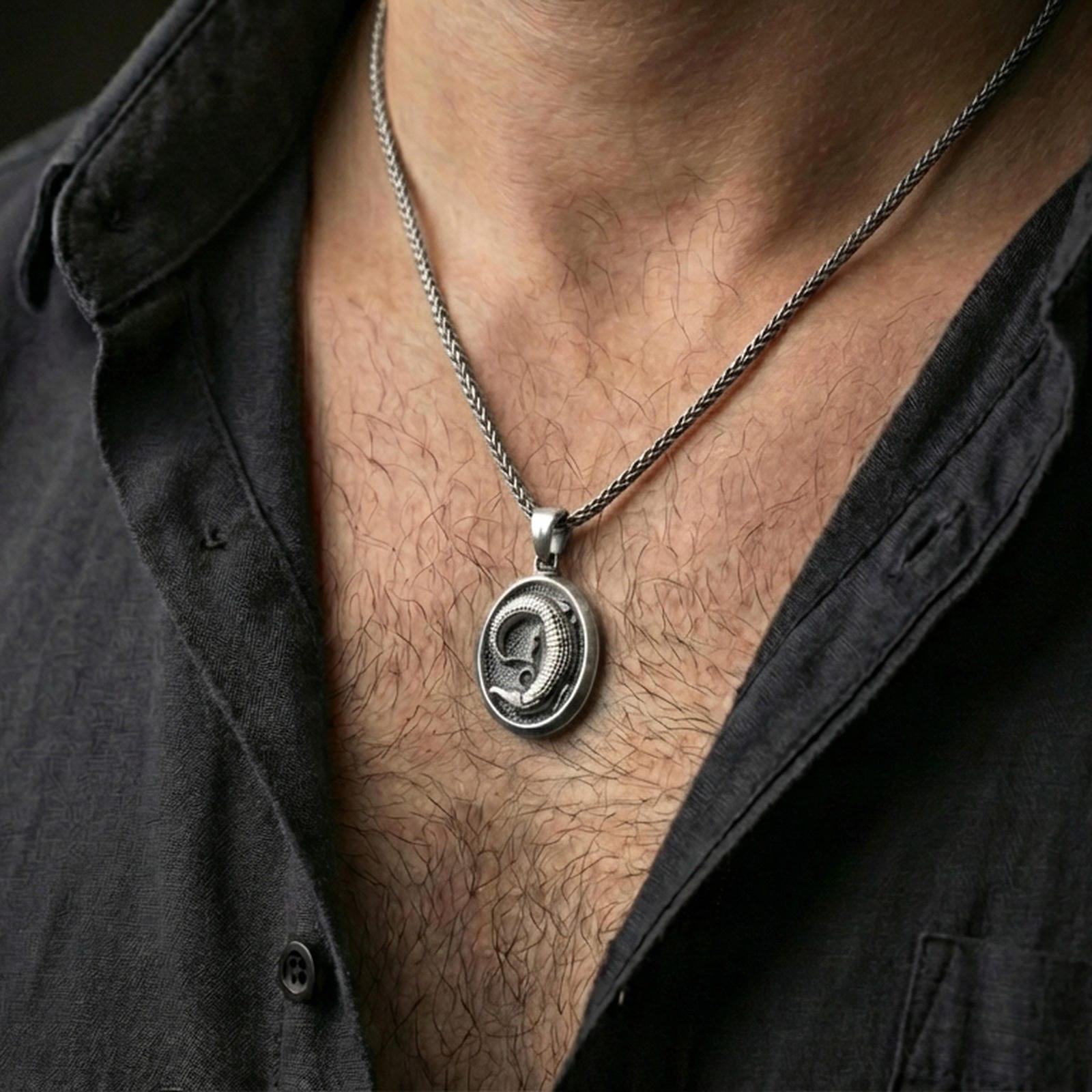 Oxidized crocodile pendant necklace worn on the neck, shown in a dark lifestyle portrait with an open shirt and masculine styling.