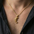 Load image into Gallery viewer, Gold plated dolphin pendant necklace worn on the neck, captured on a human model in a premium dark-toned lifestyle frame.

