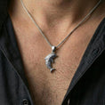 Load image into Gallery viewer, Polished silver dolphin pendant necklace worn on the neck, shown against the chest in a clean and elegant everyday wear composition.
