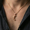 Load image into Gallery viewer, Rose gold plated dolphin pendant necklace worn on the neck, presented in a close-up lifestyle shot with a refined masculine aesthetic.
