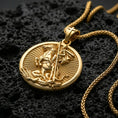 Load image into Gallery viewer, Gold plated Saint George necklace with mounted saint motif, spear weapon, and detailed round devotional scene showcased on black volcanic rock in a refined macro jewelry image
