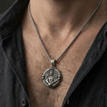 Load image into Gallery viewer, Oxidized Saint Michael pendant with winged warrior and sword worn on the neck in a lifestyle jewelry shot, styled against the chest for a bold and protective look
