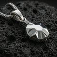 Load image into Gallery viewer, Polished silver origami tortoise pendant necklace displayed on black volcanic rock, shown in a refined macro product shot with crisp geometric facets.
