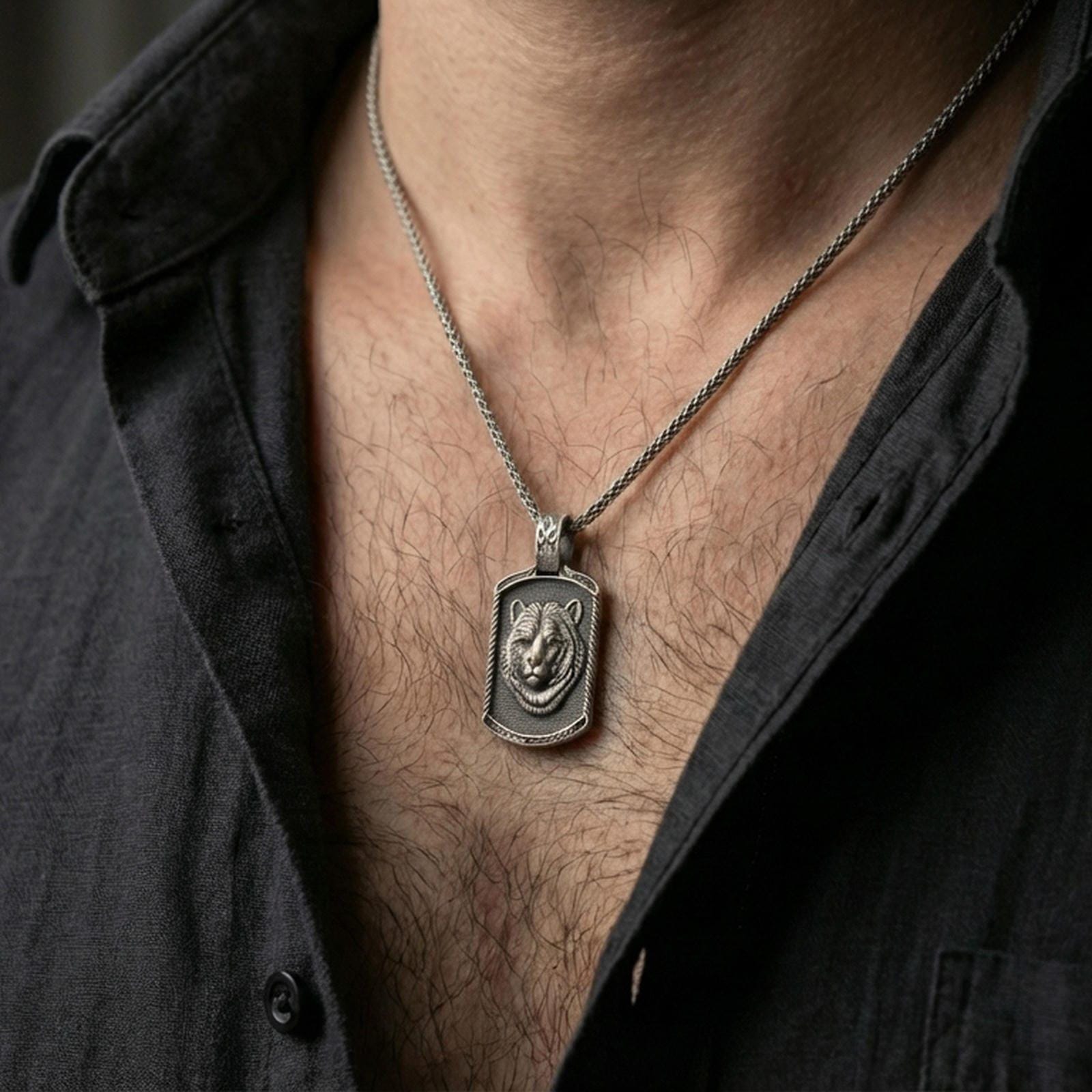 Oxidized bear pendant necklace worn on the neck, styled in a dark lifestyle portrait with an open shirt and masculine presentation.