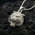 Load image into Gallery viewer, Polished silver tiger lion pendant necklace displayed on black volcanic rock, shown in a refined macro product shot with detailed feline face sculpting.
