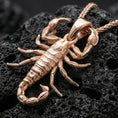 Load image into Gallery viewer, Rose gold plated scorpion pendant necklace on dark volcanic rock, photographed in a detailed premium studio macro view.
