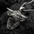Load image into Gallery viewer, Sterling silver buffalo head pendant necklace with an oxidized finish resting on textured volcanic rock, captured in a close-up premium studio composition.
