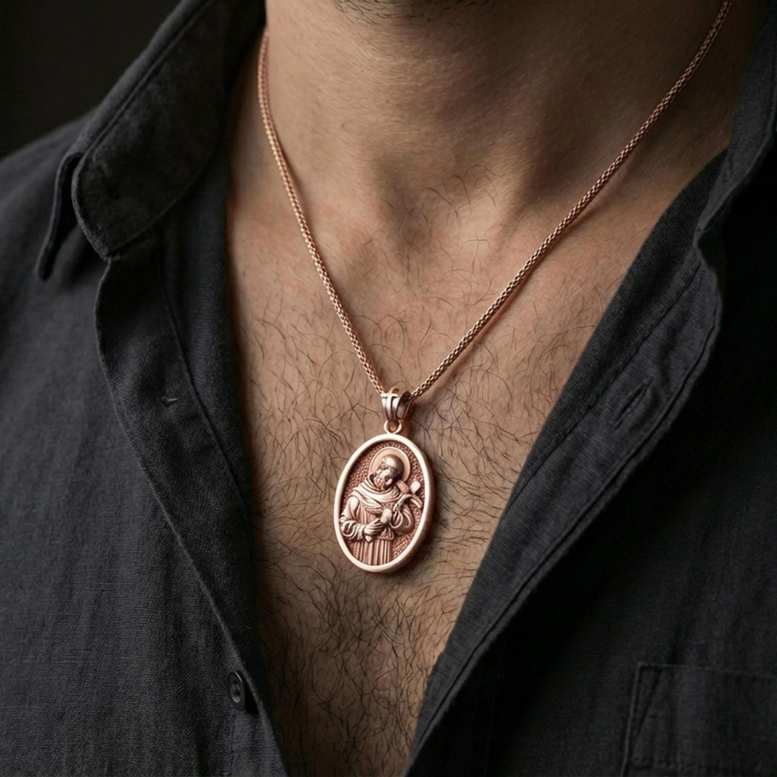 Rose gold plated Saint Francis pendant with haloed figure and devotional cross worn on the neck in a refined lifestyle shot with a warm and elegant presentation