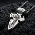 Load image into Gallery viewer, Polished silver Saint Michael medal cross with detailed angel warrior relief, ornate cross form, and engraved script at the top placed on textured volcanic rock in a premium studio product shot
