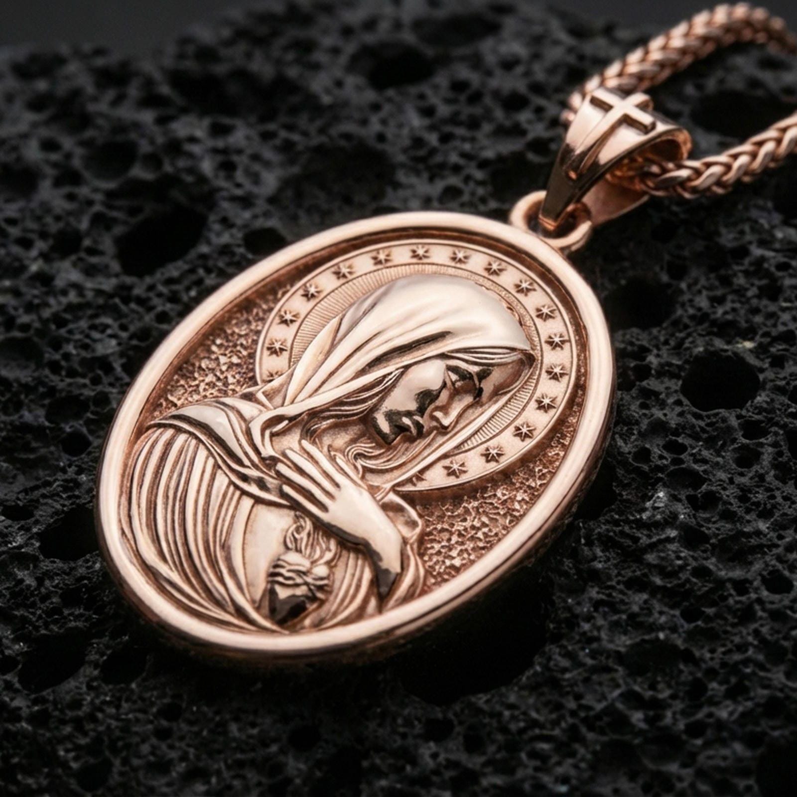 Rose gold plated Virgin Mary necklace with sacred heart motif, serene devotional portrait, and oval medallion design resting on volcanic rock in an elegant close-up product presentation