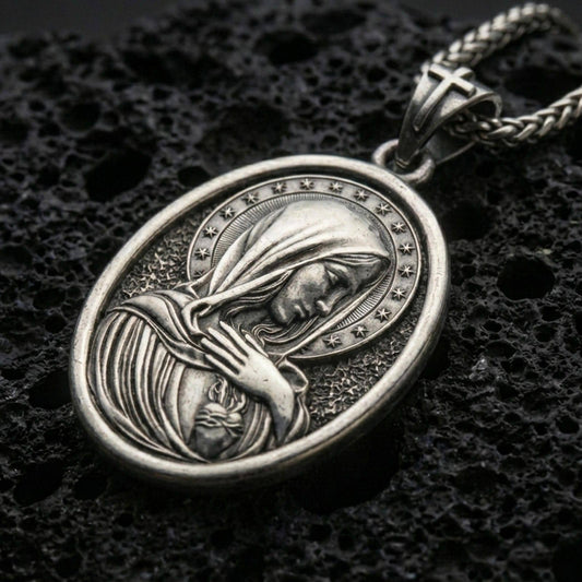 Oxidized Immaculate Heart Virgin Mary pendant with halo of stars and devotional portrait displayed on dark volcanic rock in a close-up luxury jewelry composition