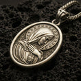 Load image into Gallery viewer, Bronze Immaculate Heart Virgin Mary pendant with halo of stars and devotional portrait displayed on dark volcanic rock in a close-up luxury jewelry composition
