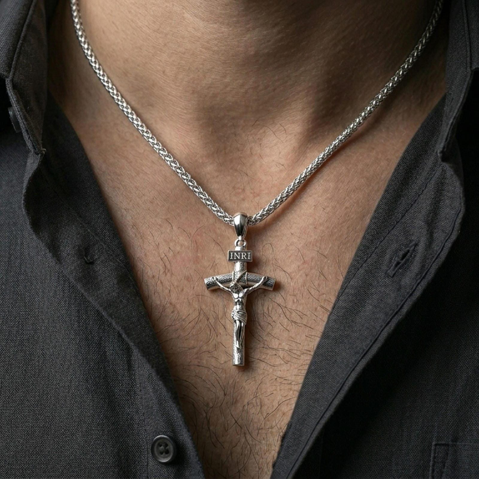 Polished silver Jesus crucifix necklace with detailed corpus and INRI plaque worn on the neck in a close lifestyle frame, highlighting the sacred relief and classic cross design