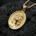 Load image into Gallery viewer, Gold plated Jesus Christ pendant with detailed crown of thorns portrait, radiant halo motif, and oval medallion design showcased on black volcanic rock in a refined macro jewelry image
