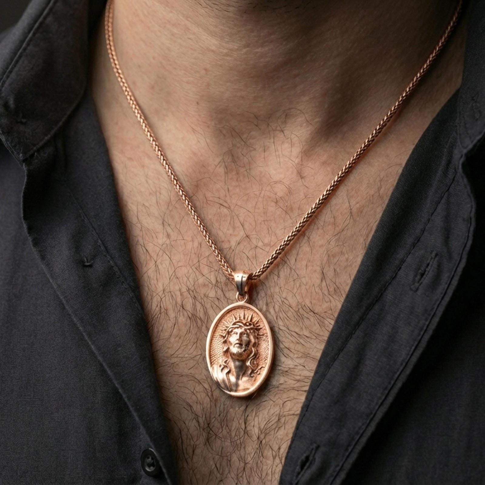 Rose gold plated religious Jesus medal with sacred portrait relief worn on the neck in a refined lifestyle shot with a warm and elegant presentation