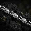 Load image into Gallery viewer, Polished silver evil eye link chain necklace displayed on black volcanic rock, shown in a refined macro product shot with engraved protective motif details.
