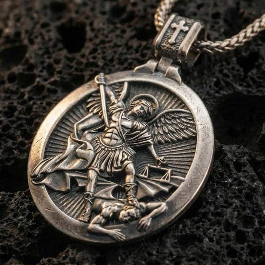 Sterling silver Saint Michael pendant necklace with an oxidized finish resting on textured volcanic rock, captured in a close-up premium studio composition.