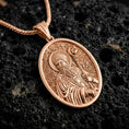 Load image into Gallery viewer, Rose gold plated Saint Patrick pendant necklace on dark volcanic rock, photographed in a detailed premium studio macro view.
