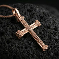 Load image into Gallery viewer, Rose gold plated Orthodox cross pendant necklace on dark volcanic rock, photographed in a detailed premium studio macro view.
