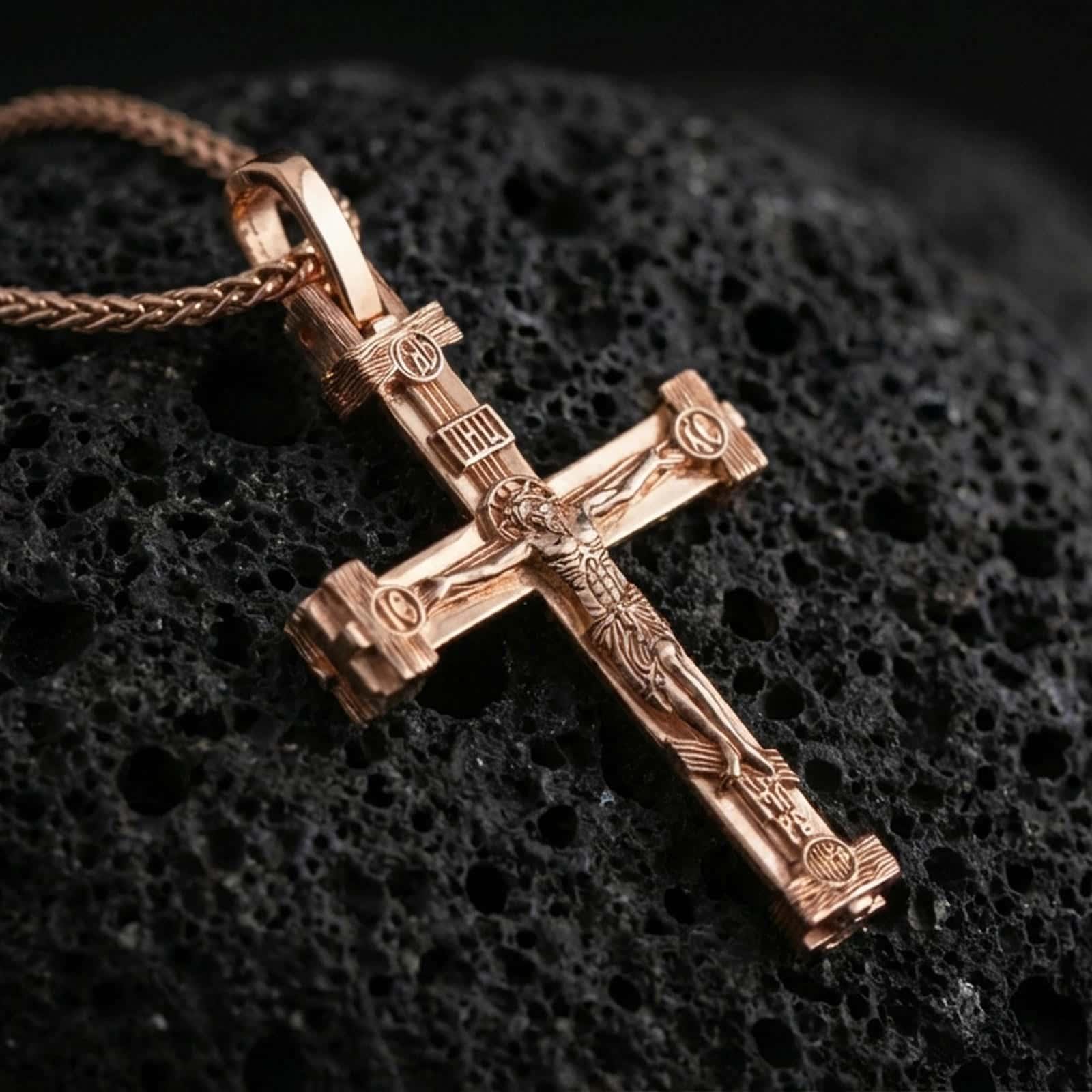 Rose gold plated Orthodox cross pendant necklace on dark volcanic rock, photographed in a detailed premium studio macro view.