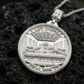 Load image into Gallery viewer, Polished silver Christian pendant with Last Supper relief on the front and Lord’s Prayer engraving on the back placed on textured volcanic rock in a premium studio product shot
