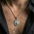 Load image into Gallery viewer, Polished silver Christian Sacred Heart medal worn on the neck in a close lifestyle frame, highlighting the oval silhouette and detailed religious relief
