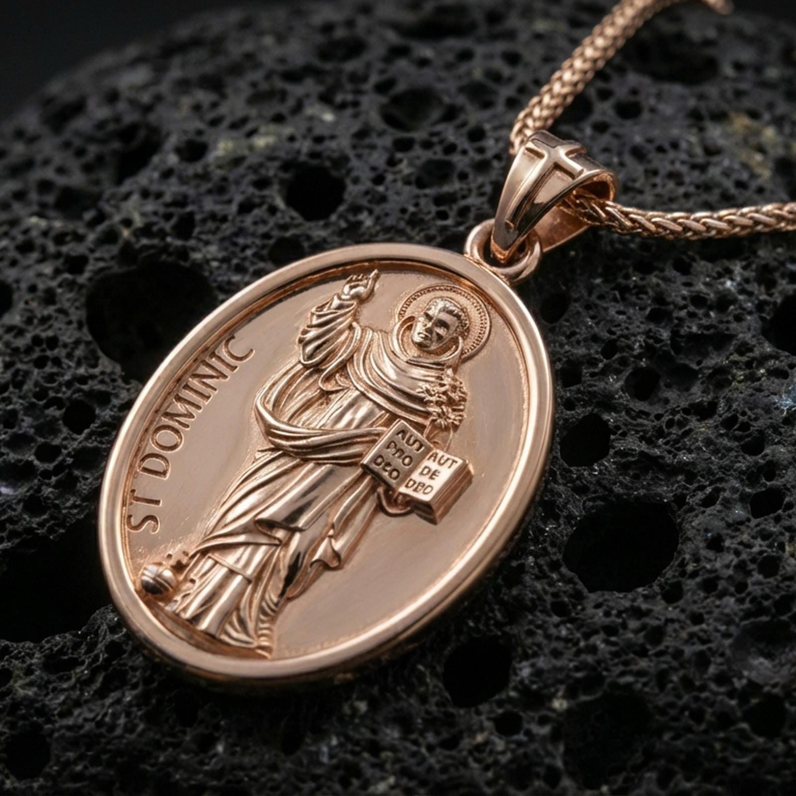 Rose gold plated oval Saint Dominic necklace with halo detail, devotional figure, and engraved religious design resting on volcanic rock in an elegant close-up product presentation