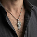Load image into Gallery viewer, Oxidized angel wing pendant worn on the neck in a lifestyle jewelry shot, styled against the chest for a bold and symbolic look
