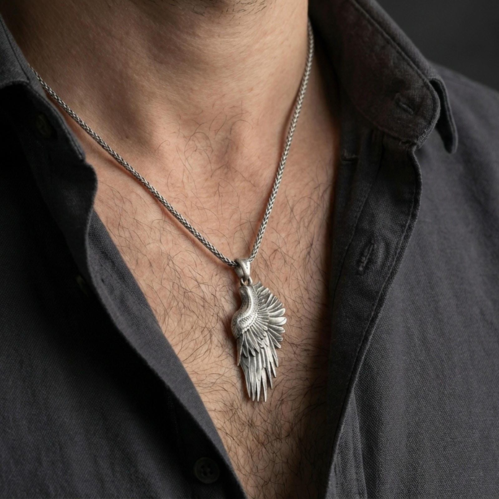 Oxidized angel wing pendant worn on the neck in a lifestyle jewelry shot, styled against the chest for a bold and symbolic look