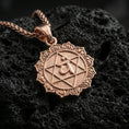 Load image into Gallery viewer, Rose gold plated heart chakra pendant with sacred Anahata sign, star geometry, and decorative sun-like edge resting on volcanic rock in an elegant close-up product presentation
