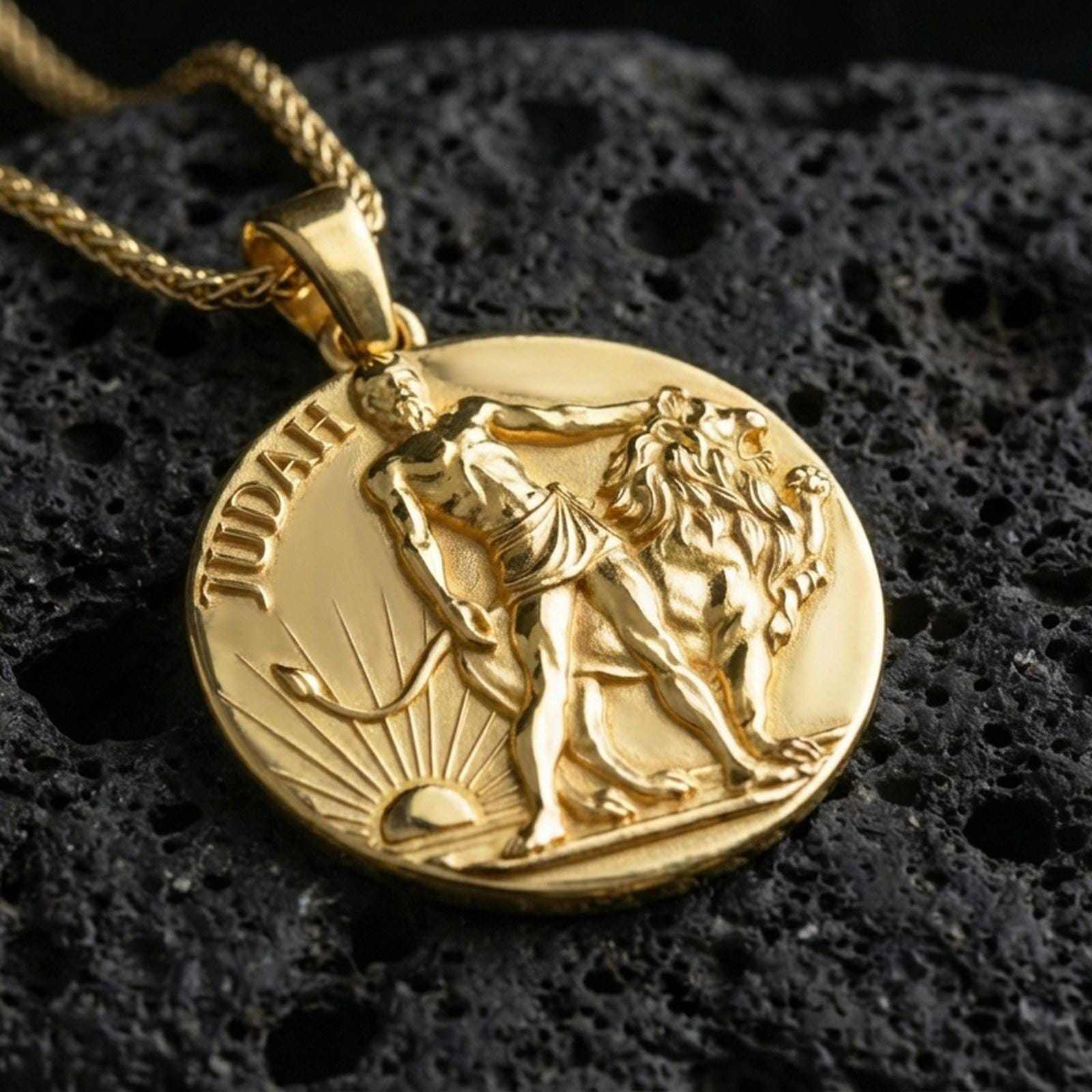 Gold plated Lion of Judah necklace with detailed lion symbol, round devotional form, and rising sun scene showcased on black volcanic rock in a refined macro jewelry image