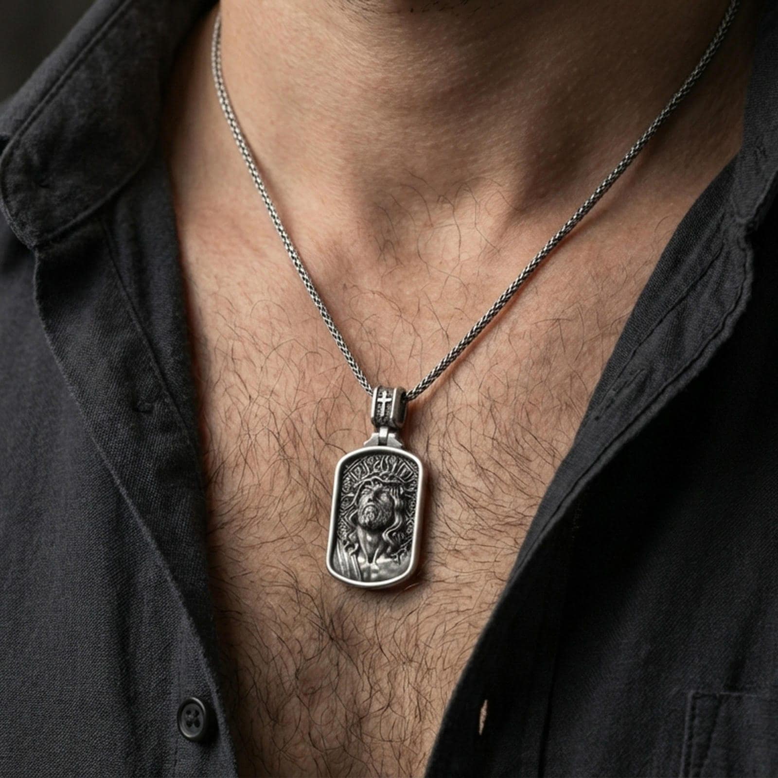 Oxidized Jesus Christ pendant with crown of thorns worn on the neck in a lifestyle jewelry shot, styled against the chest for a bold and devotional look