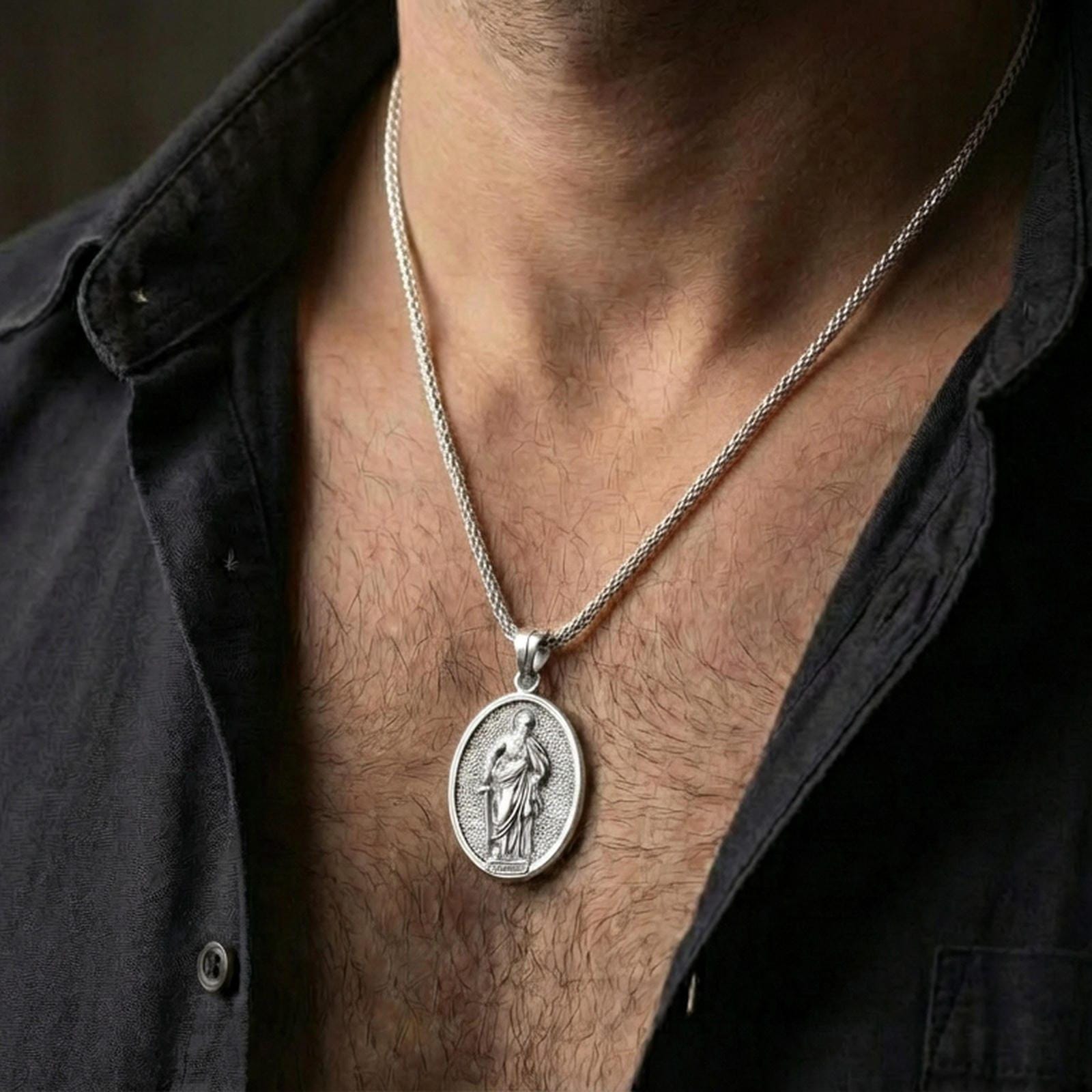 Polished silver Saint Paul medallion with saint relief and halo motif worn on the neck in a close lifestyle frame, highlighting the oval silhouette and sacred detailing