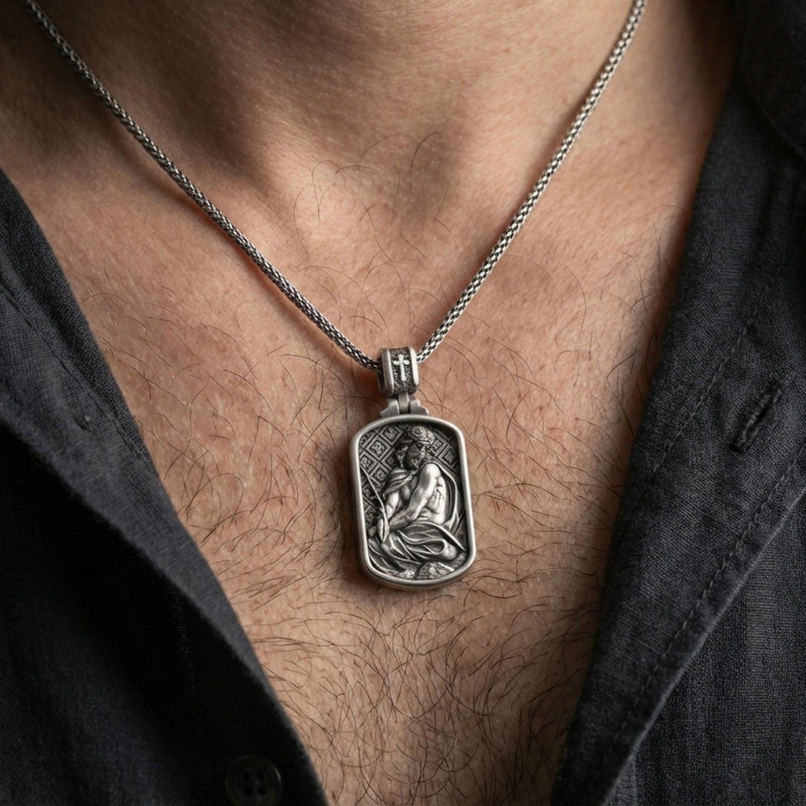 Oxidized Jesus Christ pendant with seated sacred figure and crown of thorns worn on the neck in a lifestyle jewelry shot, styled against the chest for a bold and devotional look