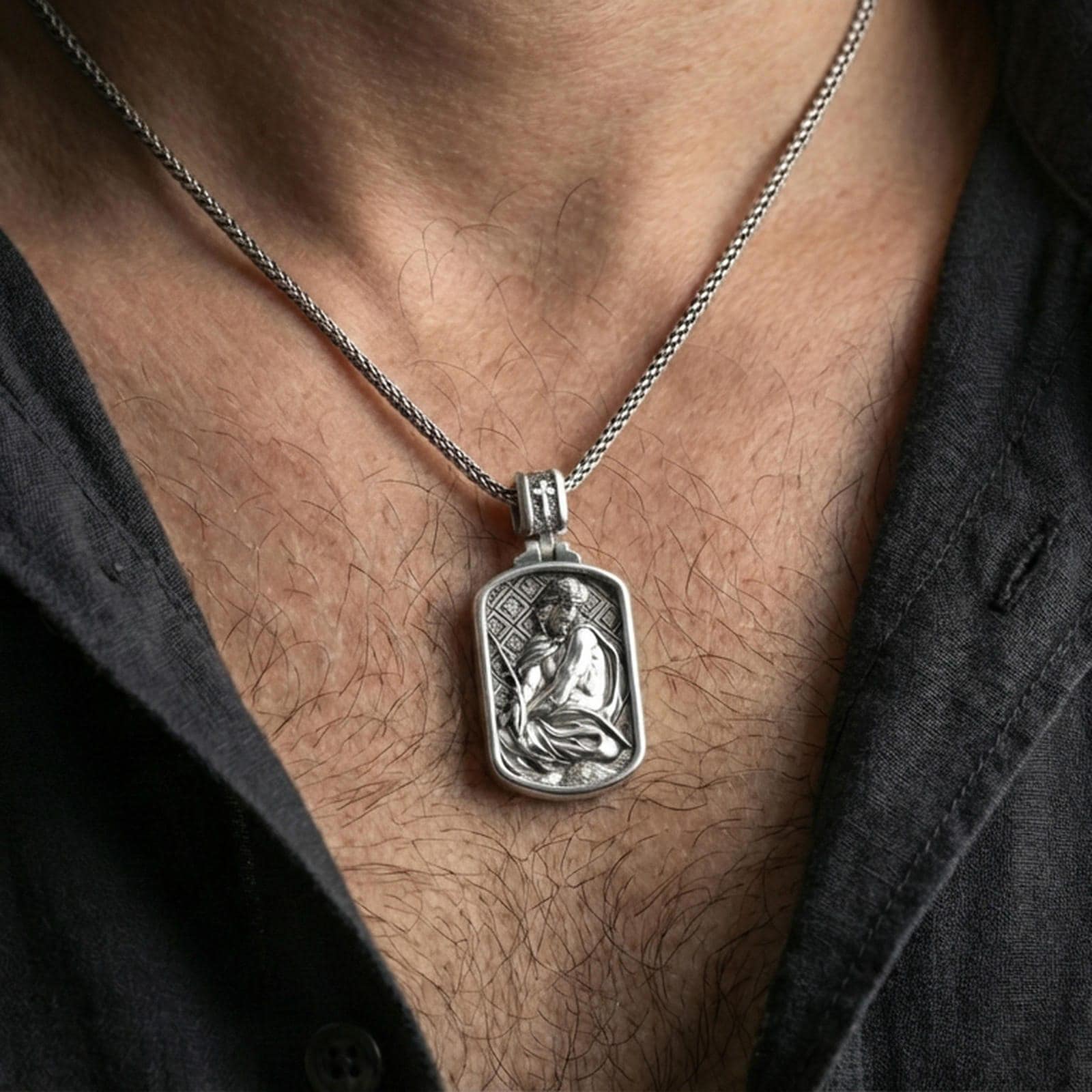 Polished silver Jesus medallion with seated Christ relief worn on the neck in a close lifestyle frame, highlighting the framed silhouette and detailed sacred portrait